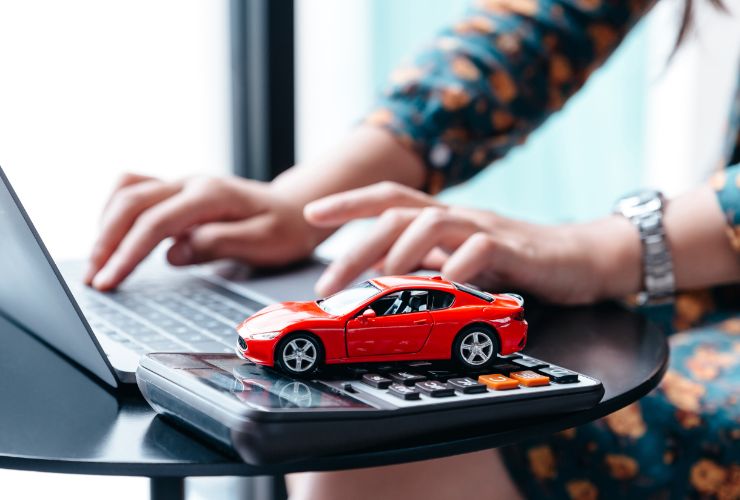 donna al pc con modellino auto e calcolatrice