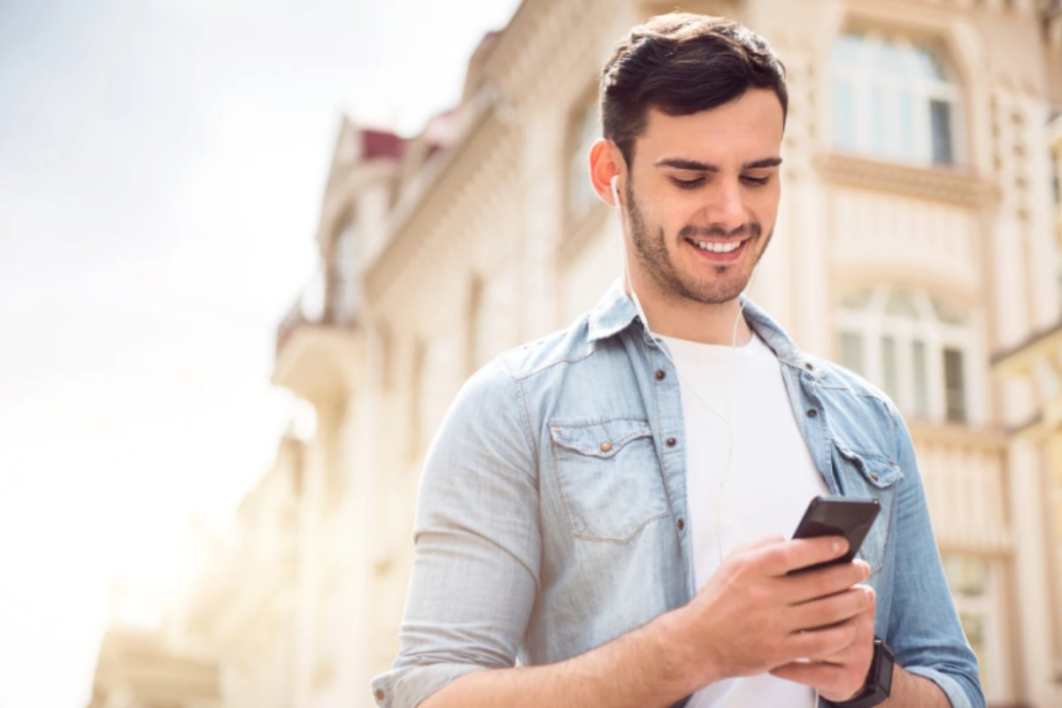 uomo che sorride con in mano il cellulare
