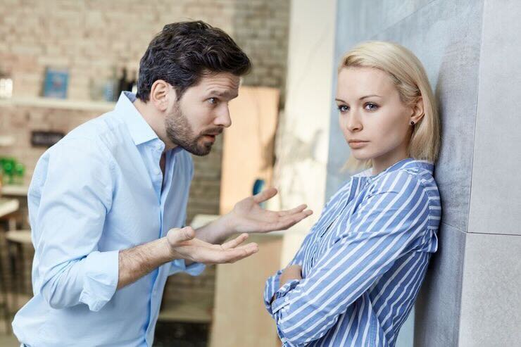 Uomo discute con ragazza di fronte a lui che guarda altrove 
